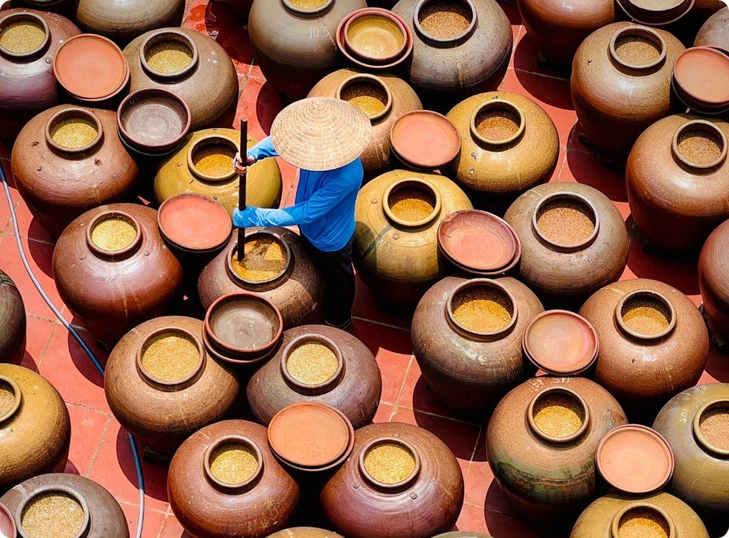 Vue aérienne de jarres de fermentation et d'un artisan au chapeau conique